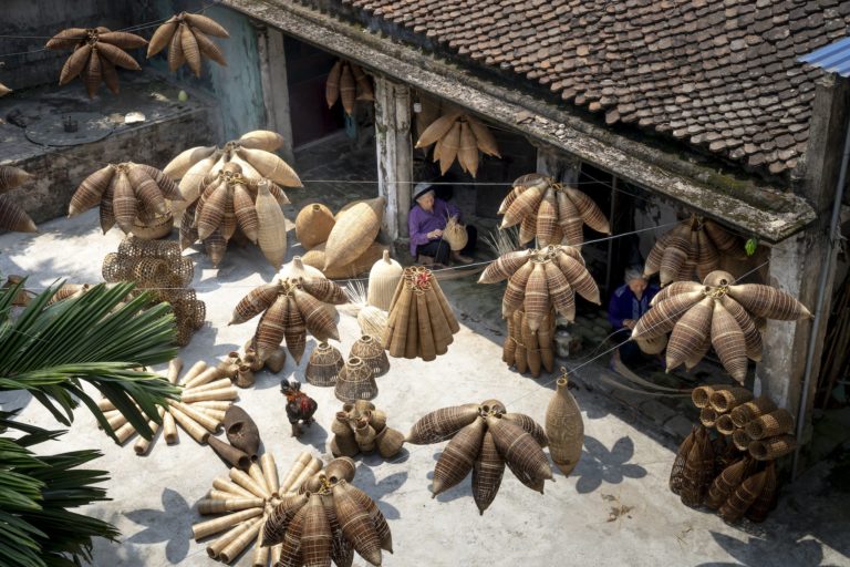 From above of people sitting and making bamboo fish traps while working on local bazaar in Vietnam in daylight